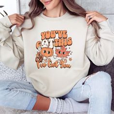 "Stay cozy in this super soft Occupational Therapy sweatshirt with retro Fall vibes. This Fall sweater features a cute retro cartoon pumpkin holding hands with a Fall leaf, with the inspirational phrase \"You've gOT this & I've gOT you\". Whether you're dressing up for your OT patients, or just want to get cozy and relax at home, you are sure to fall in love with this soft and comfy sweatshirt! Gildan 18000 Brand Sweatshirts  Unisex Adult Sizing Rolled Sleeves in pictures are for styling purpose Trendy Fall Sweatshirt With Character Print, Trendy Character Print Sweatshirt For Fall, Trendy Cartoon Print Tops For Fall, Fun Fall Tops With Cartoon Print, Retro Soft-washed Sweatshirt For Fall, Retro Long Sleeve Sweatshirt With Cartoon Print, Relaxed Fit Cartoon Print Top For Fall, Cute Orange Tops With Cartoon Print, Cute Fall Sweatshirt With Character Print