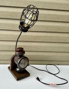 a lamp that is sitting on top of a wooden stand with a wire attached to it