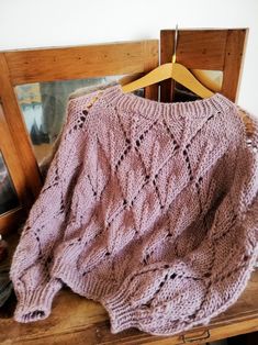 a pink sweater sitting on top of a wooden table next to an old photo frame