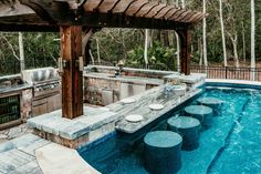 an outdoor kitchen and hot tub in the middle of a pool with stone steps leading up to it