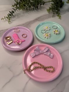 three pink and blue plates with jewelry on them