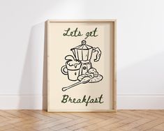 a framed poster with the words let's get breakfast on it in front of a white wall