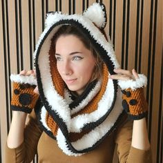 a woman wearing a knitted scarf with a bear hood and mittens on her head