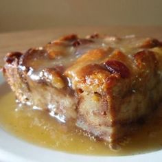 a piece of bread pudding on a white plate with caramel sauce around the crust