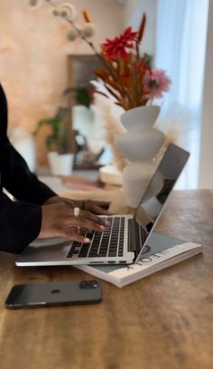 a woman sitting at a table using a laptop computer on top of a wooden desk