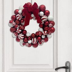 a red and white christmas ornament wreath on a door