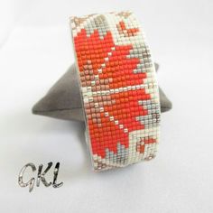 an orange and white beaded bracelet on a metal stand