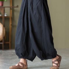 a woman in black pants and sandals is standing on the floor with her hands behind her back