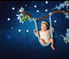 a baby is laying down in a hammock with stars on the sky behind it