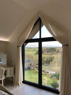 a bedroom with a large window overlooking the countryside