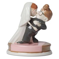 a figurine of a bride and groom kissing each other on a pink base