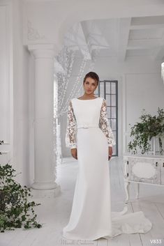 a woman in a white wedding dress standing on the floor with her arms behind her back