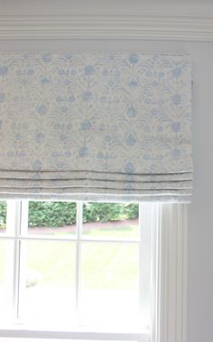 a window with a blue and white flowered valance hanging from it's side