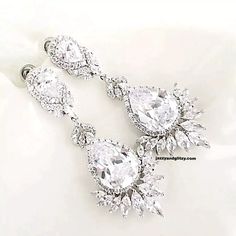 two pairs of diamond earrings are shown on a white surface, one is in the shape of an earring