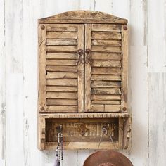 an old wooden cabinet and hat hanging on the wall