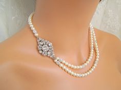 "This pearl necklace is created with a vintage look embellishment and Austrian pearls in cream color. Focal point is embellished with various sizes of Austrian chatons crystals.  Inner strand measures approximately 17\" long.  Necklace comes with 2\" extender chain for additional length. Pearls measure 6 mm and are accented with rhinestone balls for a glamorous look!   Finished off with a filigree attached to a lobster claw closure.  Focal point measures approximately 1 3/4\" by 1\" wide.  What a romantic piece for any bride! Austrian elements used: 6 mm cream pearls.  Embellishment has some Austrian crystals and rhinestones. Coordinating Earrings, https://www.etsy.com/listing/97637197/bridal-earringspearl-rhinestone?ga_search_query=colleen https://www.etsy.com/listing/92717554/clip-on-ear Wedding Necklace Pearl, Bridal Jewelry Pearl, Bridal Jewlery, Wedding Choker Necklace, Champagne Necklace, Wedding Earrings Vintage, Bridal Bracelet Pearl, Bridal Earrings Studs, Bridal Pearl Necklace