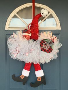 a christmas wreath hanging on the front door with santa's hat and boots attached to it