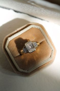 an engagement ring sitting on top of a velvet box