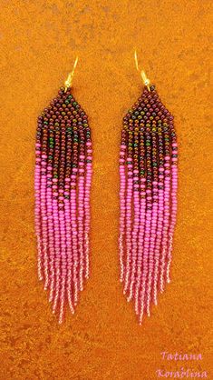 two pairs of pink and black beaded earrings on a brown surface with gold earwires