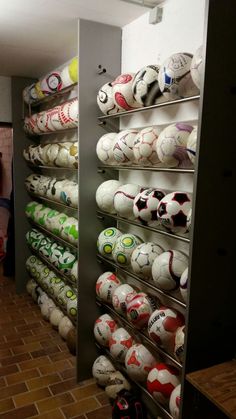 soccer balls are lined up on shelves in a room