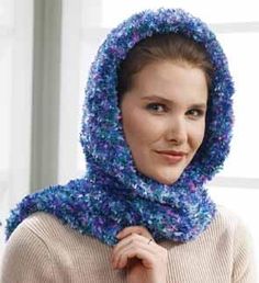 a woman wearing a blue knitted hood and scarf over her head, looking at the camera