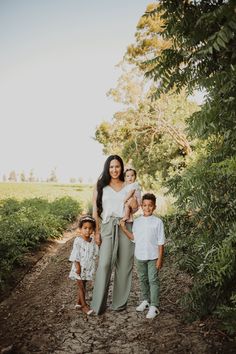 a woman and two children standing on a dirt path