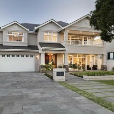 a large house with two garages in front of it and landscaping around the driveway