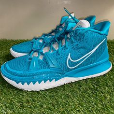 a pair of blue and white nike shoes on green grass in front of a wall