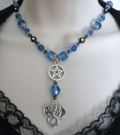 "This beautiful necklace has blue faceted beads, black rhinestone beads, seed beads, pewter silver accent beads, sterling silver plated bead caps, pewter silver pentacle and pewter silver dragon. 18\" long. Toggle clasp." Gothic Black Beads Jewelry For Halloween, Gothic Black Beads Halloween Jewelry, Blue Gothic Metal Necklace, Gothic Dangle Necklaces For Jewelry Making, Gothic Beaded Necklaces For Halloween, Gothic Beaded Jewelry Gift, Gothic Beaded Jewelry For Gift, Gothic Beaded Necklace For Gift, Gothic Blue Metal Jewelry