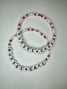 two beaded bracelets with words and hearts are shown on a white table top