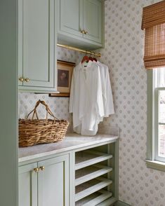 a laundry room with green cabinets and wallpaper