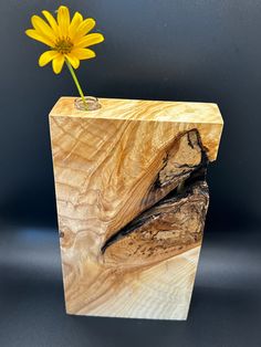 a wooden vase with a yellow flower in it