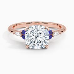 a rose gold engagement ring with an oval cut diamond and blue sapphire stones on the side