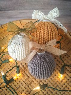 three knitted ornaments are sitting on a wicker tray with string lights around them