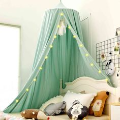 a child's bedroom with stuffed animals on the bed and green canopy over it