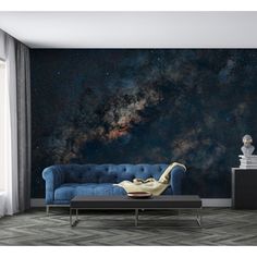 a living room with a blue couch and stars in the sky wall mural on it