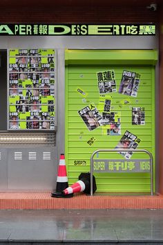 a green store front with pictures on the wall and a traffic cone in front of it