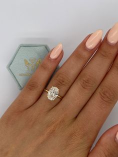 a woman's hand with a diamond ring on it and a pink manicure