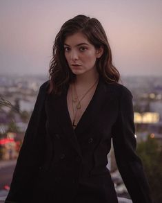 a woman standing on top of a roof next to a tall building with the city in the background