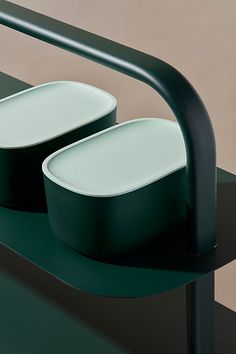 two white bowls sitting on top of a green table next to a black metal frame