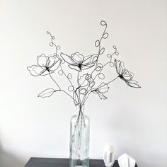 a vase filled with flowers sitting on top of a table next to a white wall