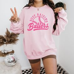 Busy Raising Ballers Sweatshirt - Softball Sweater - Baseball Sweatshirt - Sports Mom - Mother's Day Gift for Mom, Mom Gift Baseball Hoodie  Please pay attention to which of the Hoodie and Crewneck Sweatshirt options you choose. When you choose the Hoodie option, it will be sent with a hood. When you choose C.Neck Sweatshirt option, Crewneck Sweatshirt will be sent. Material Details Gildan and Circle Brand Unisex Long Sleeve Hoodies/ C.Neck Sweatshirt No Drawcord in Youth Hoodies For Added Safet Busy Raising Ballers, Raising Ballers, Baseball Sweatshirts, Baseball Hoodie, Baseball Gifts, Sports Mom, Youth Hoodies, Mom Gift, Mother's Day Gift