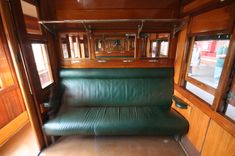 a green leather couch sitting inside of a train car