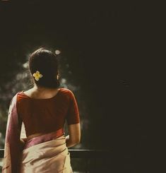 a woman in a red and white sari looks out over the water at night