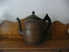 an old teapot sitting on top of a wooden shelf