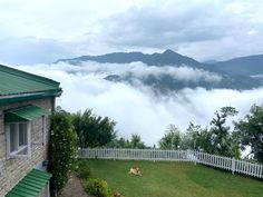 a dog laying on the grass in front of a house with mountains in the background