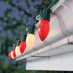 christmas lights are hanging from the side of a window sill in front of trees