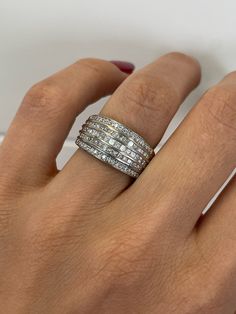 a woman's hand wearing a ring with three rows of diamonds on the band