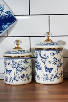 two blue and white canisters sitting on top of a wooden table