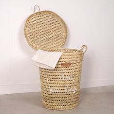 a round wicker laundry basket with a white towel hanging from the top and an oval lid